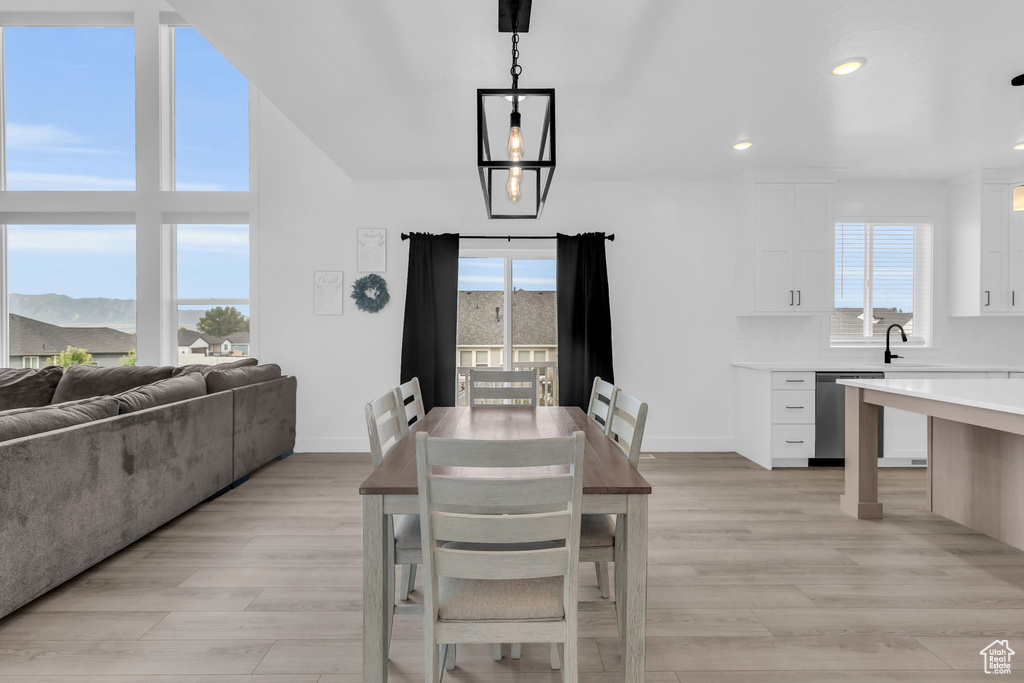 Dining area featuring a notable chandelier, sink, light hardwood / wood-style floors, and a healthy amount of sunlight