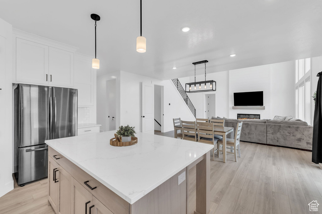 Kitchen featuring hanging light fixtures, light hardwood / wood-style flooring, stainless steel refrigerator, and a center island