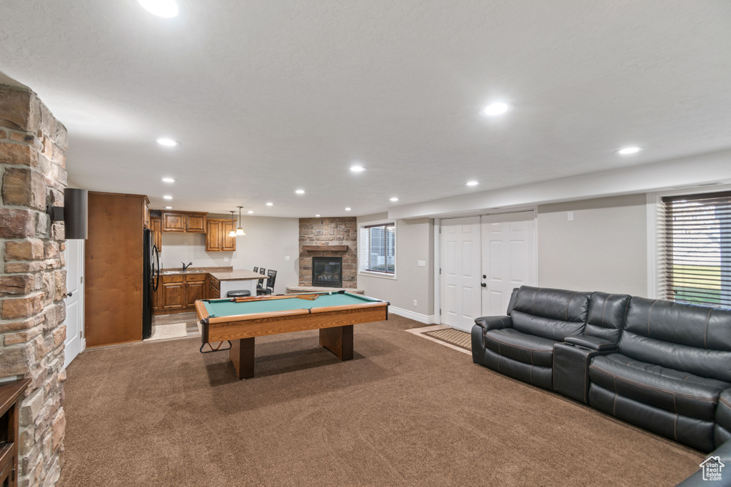 Recreation room with a stone fireplace, dark carpet, and billiards
