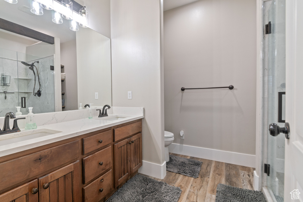 Bathroom featuring an enclosed shower, dual bowl vanity, toilet, and hardwood / wood-style flooring