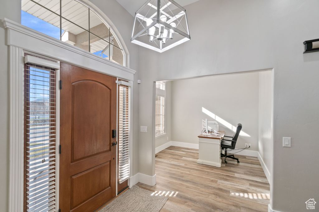 Entrance foyer featuring an inviting chandelier, a high ceiling, and light hardwood / wood-style flooring