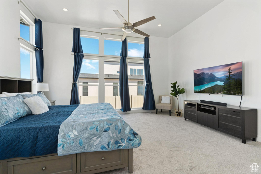 Bedroom featuring a towering ceiling, light carpet, and ceiling fan