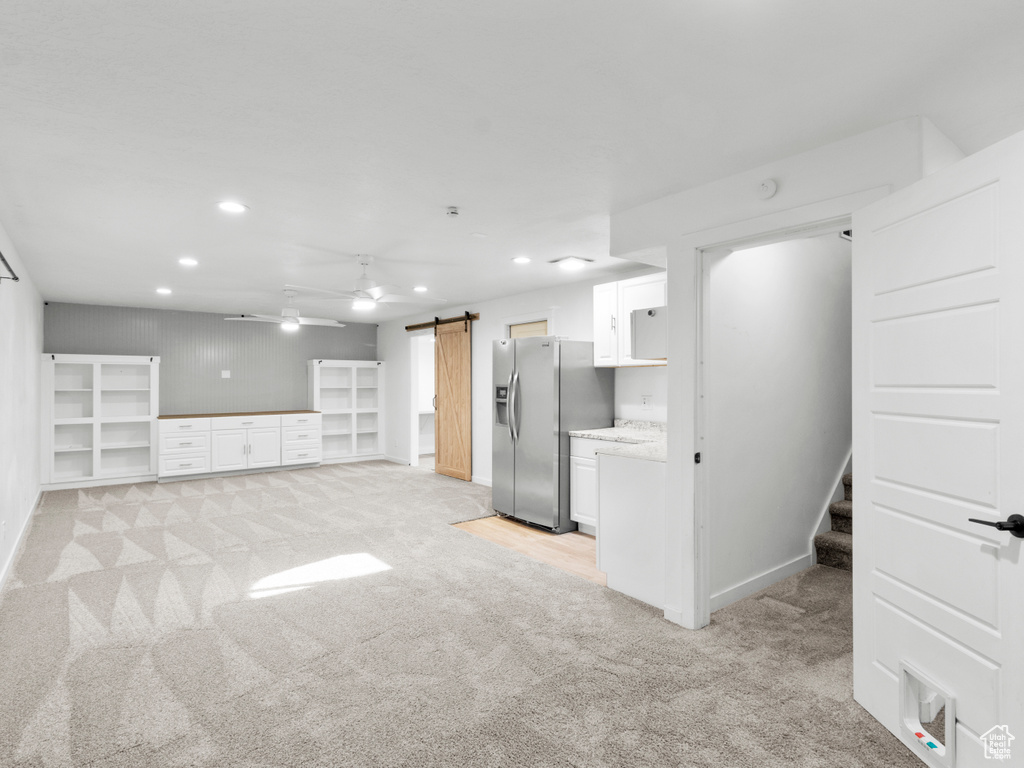 Kitchen with white cabinets, light colored carpet, a barn door, and stainless steel refrigerator with ice dispenser