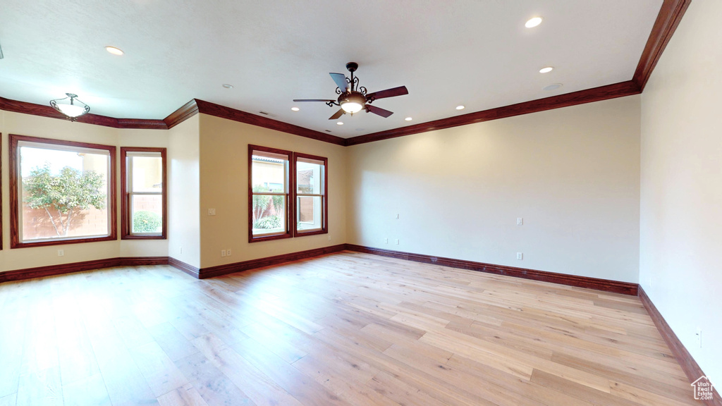 Empty room with ornamental molding, light wood-type flooring, and ceiling fan