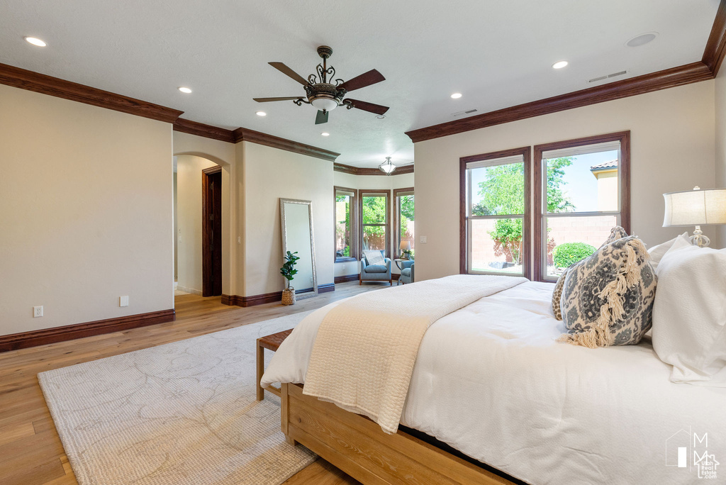 Bedroom with light hardwood / wood-style flooring, ornamental molding, and ceiling fan