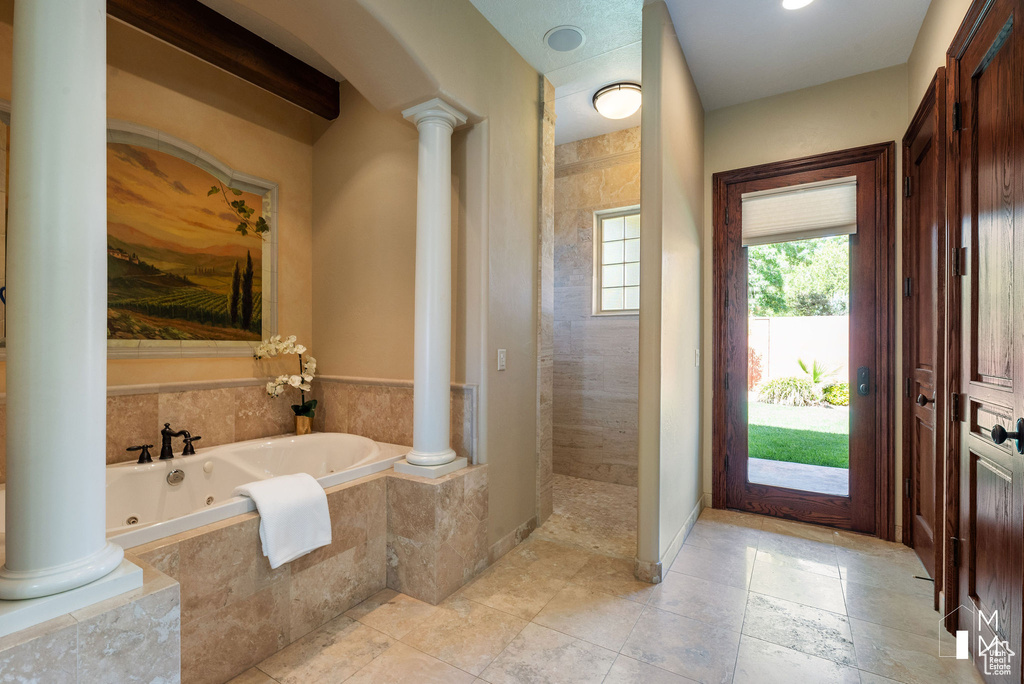 Bathroom featuring decorative columns, tile flooring, and a relaxing tiled bath