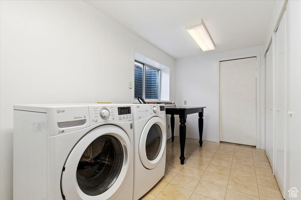 Laundry area featuring light tile flooring and washer and clothes dryer