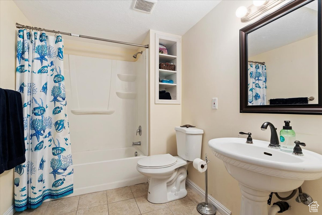 Full bathroom featuring sink, shower / bathtub combination with curtain, toilet, and tile flooring