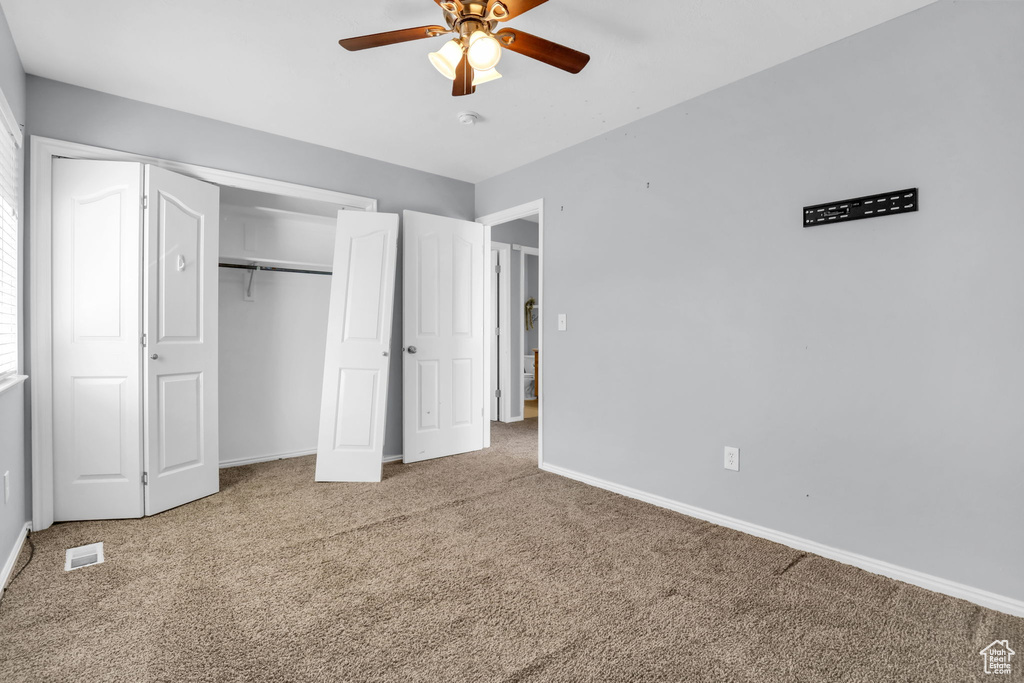 Unfurnished bedroom featuring a closet, light carpet, and ceiling fan