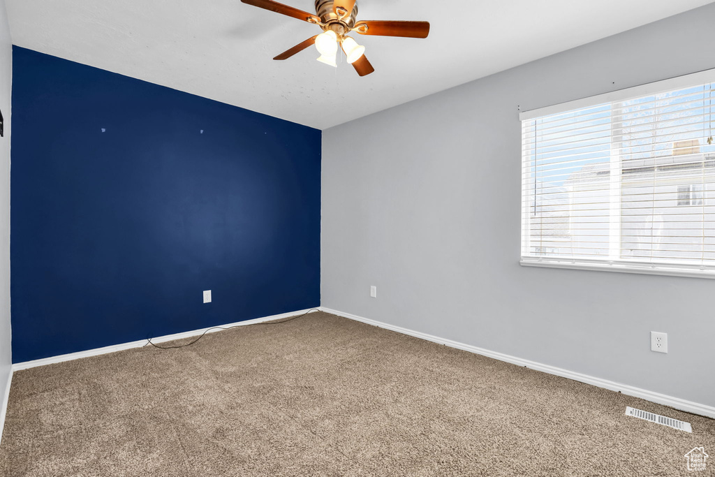 Unfurnished room with dark colored carpet and ceiling fan