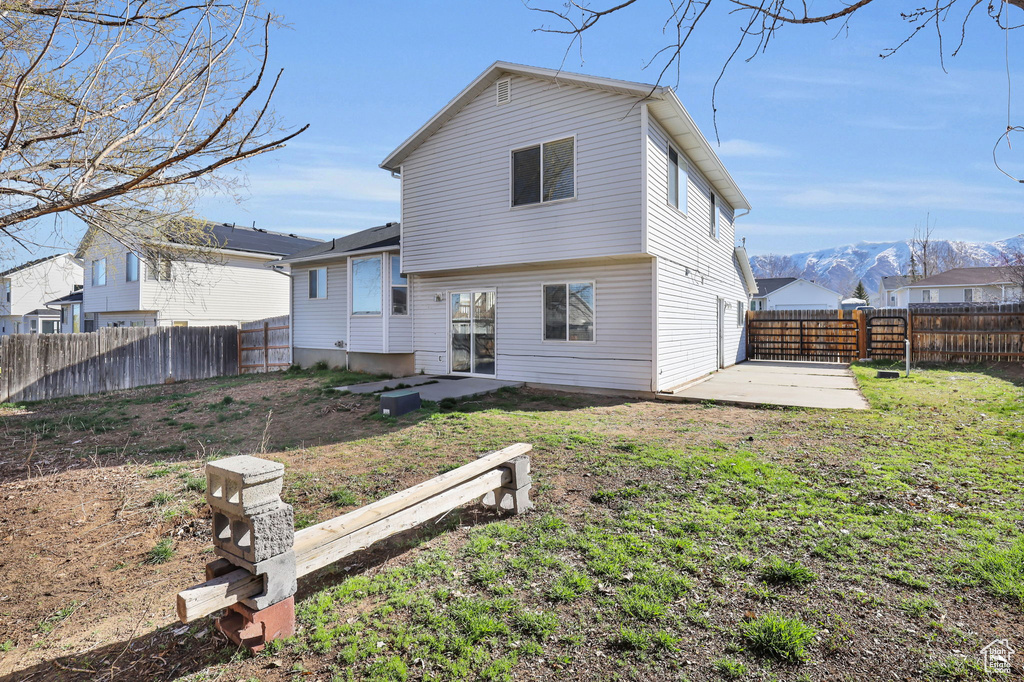 Back of property featuring a patio, a lawn, and a mountain view