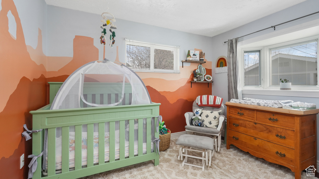Bedroom featuring a crib and light colored carpet