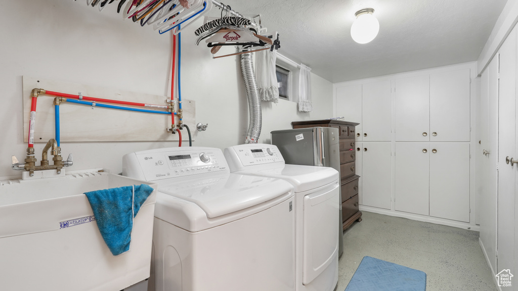 Clothes washing area featuring cabinets, sink, washing machine and dryer, and hookup for a washing machine