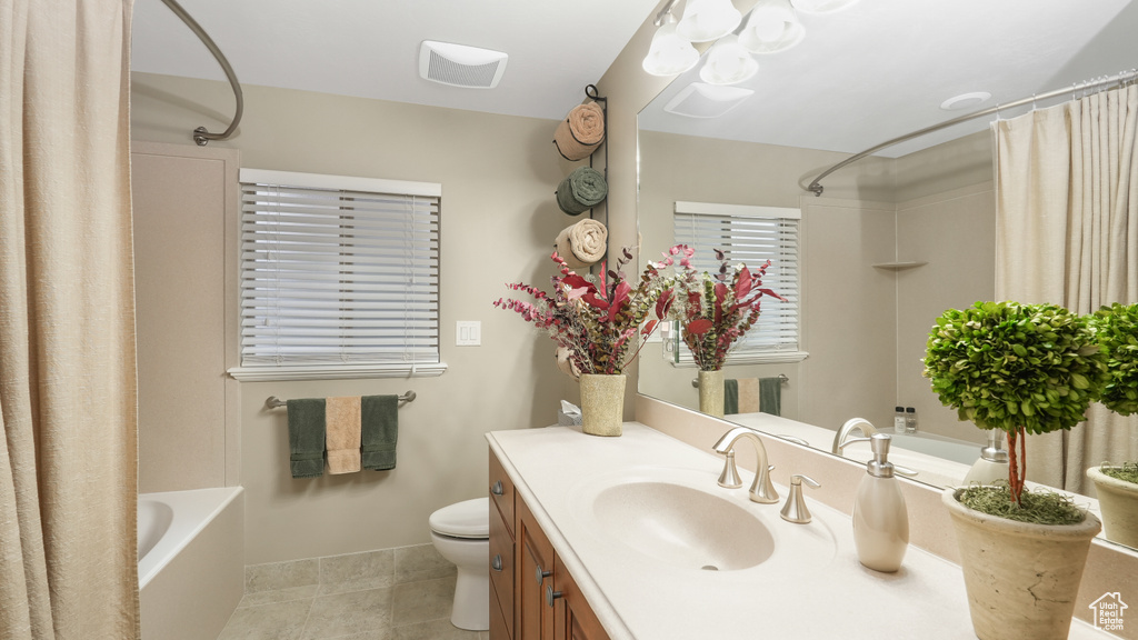 Full bathroom with vanity with extensive cabinet space, shower / bath combo with shower curtain, tile floors, and toilet