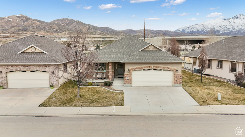 View of front of property with a mountain view, a front lawn, and a garage