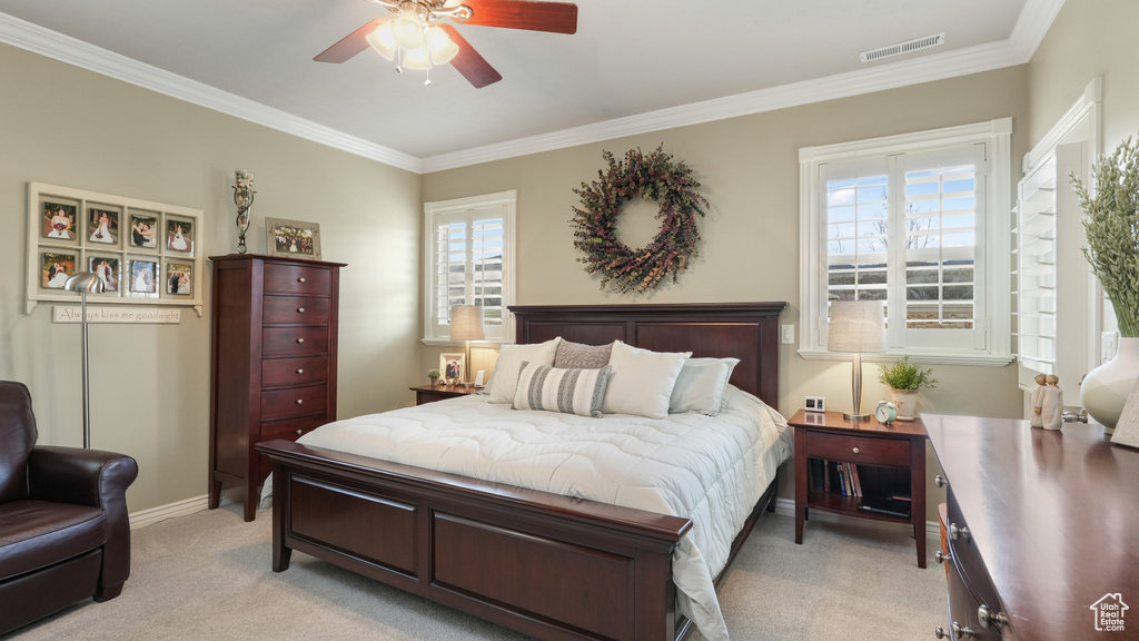 Carpeted bedroom with multiple windows, ornamental molding, and ceiling fan