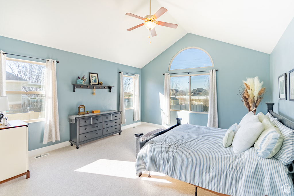 Carpeted bedroom featuring ceiling fan and high vaulted ceiling
