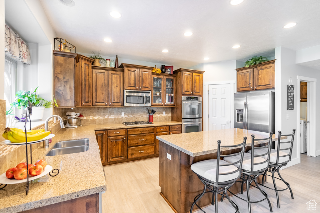 Kitchen featuring stainless steel appliances, a breakfast bar, backsplash, and light hardwood / wood-style floors