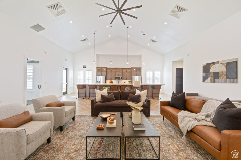 Living room with an inviting chandelier, high vaulted ceiling, and light hardwood / wood-style floors