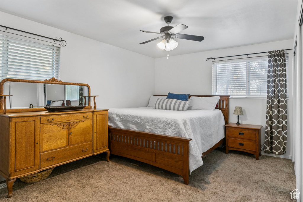 Carpeted bedroom with multiple windows and ceiling fan