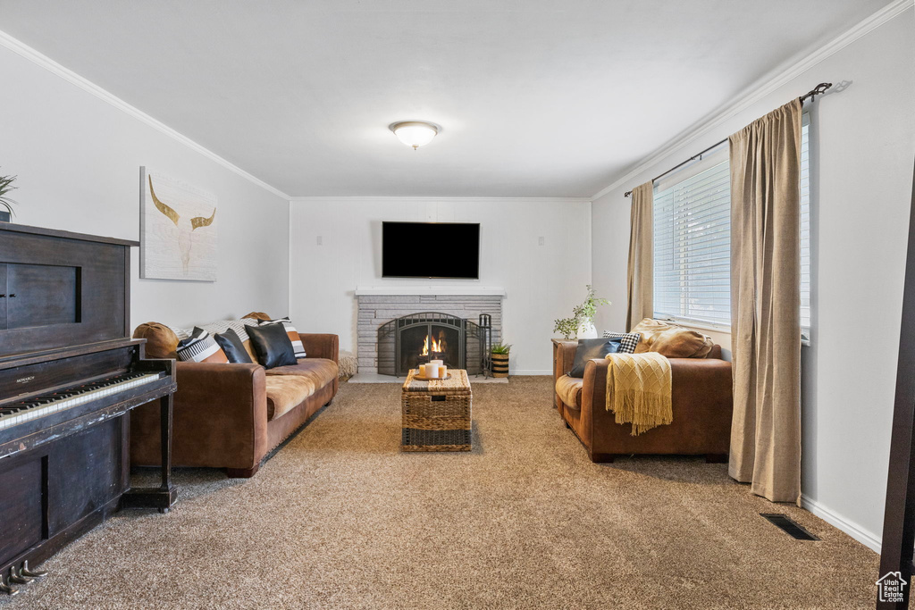 Living room featuring ornamental molding, a brick fireplace, and carpet