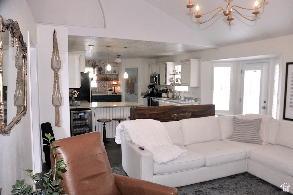Tiled living room featuring wine cooler, an inviting chandelier, lofted ceiling, and sink