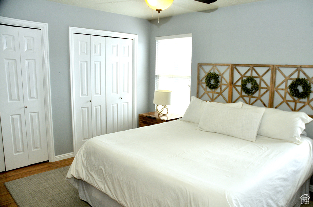 Bedroom featuring wood-type flooring, multiple closets, and ceiling fan