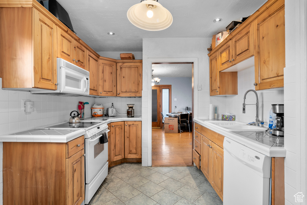 Kitchen featuring tasteful backsplash, sink, white appliances, and light tile flooring