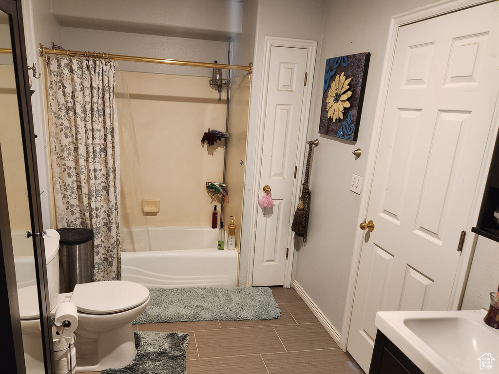 Full bathroom featuring shower / tub combo, toilet, tile floors, and vanity