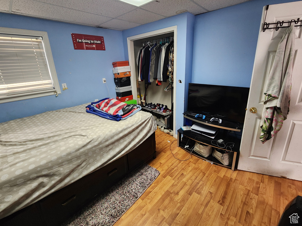 Bedroom with light hardwood / wood-style floors, a closet, and a drop ceiling