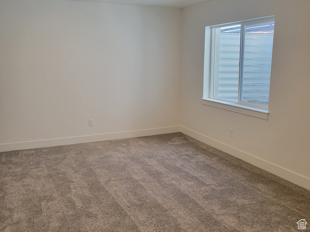 Empty room with a smoke detector and dark colored carpet