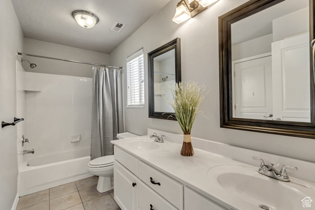 Full bathroom featuring tile floors, shower / bath combination with curtain, double sink vanity, and toilet