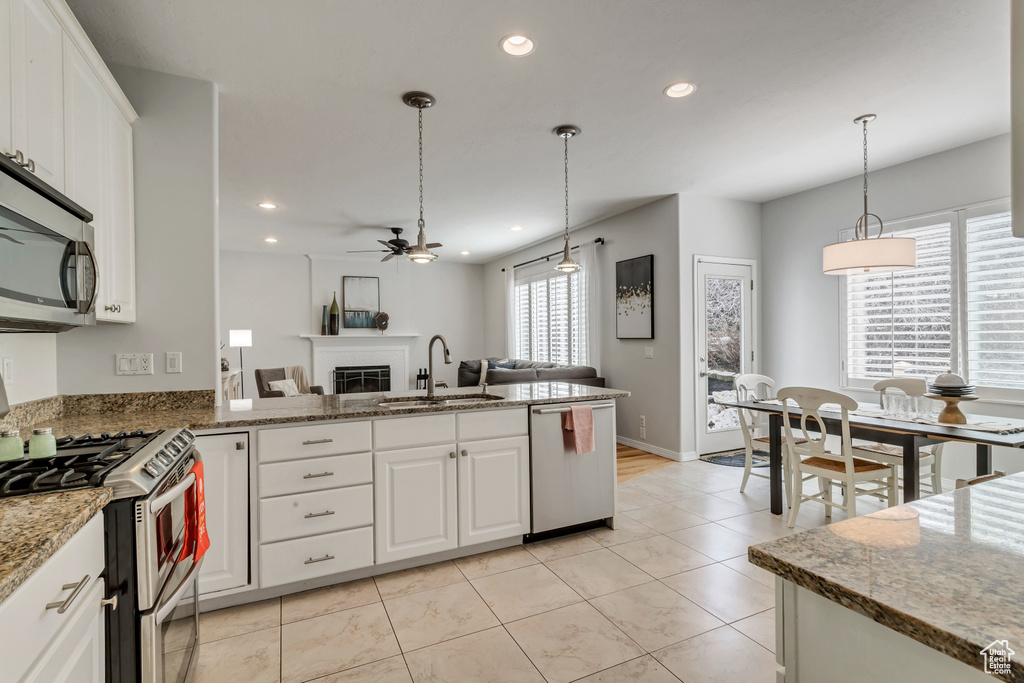 Kitchen featuring white cabinets, ceiling fan, decorative light fixtures, sink, and appliances with stainless steel finishes