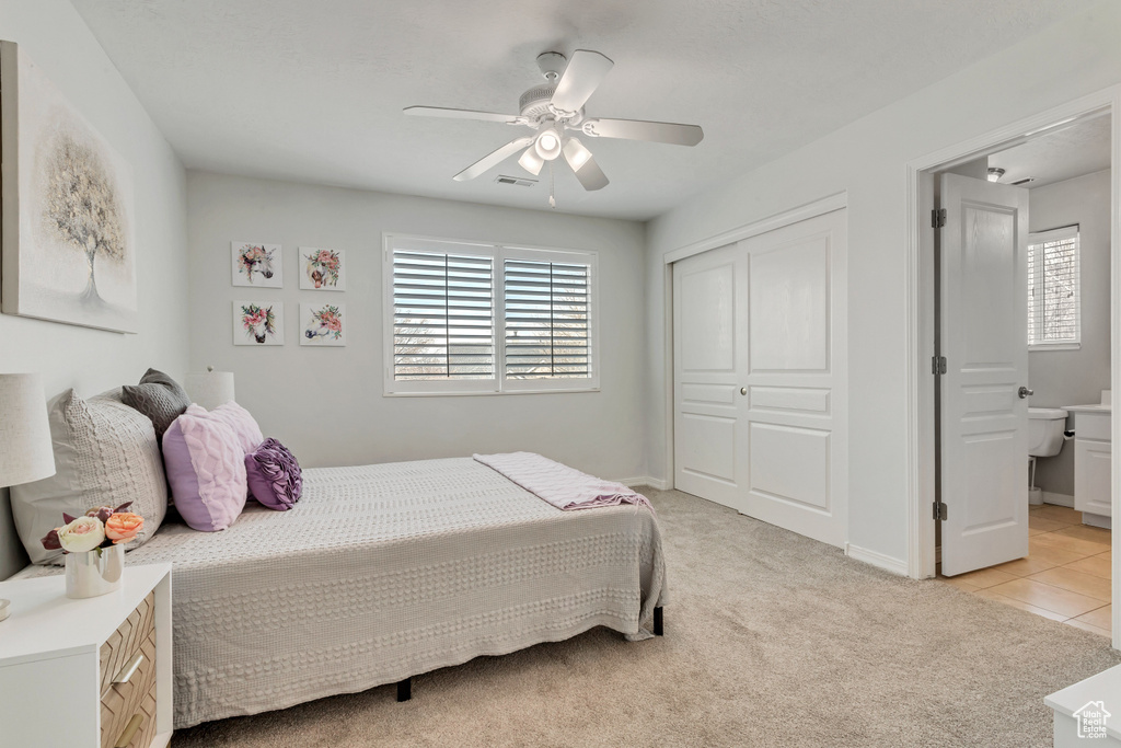 Bedroom featuring ensuite bath, a closet, light carpet, and ceiling fan