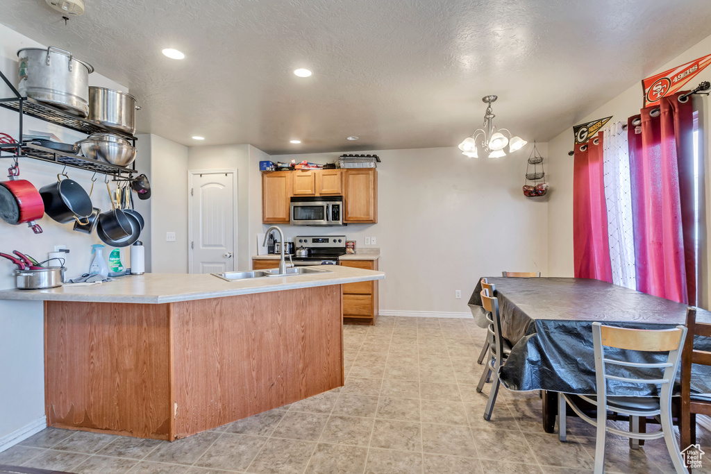 Kitchen featuring sink, a chandelier, stainless steel appliances, and light tile floors