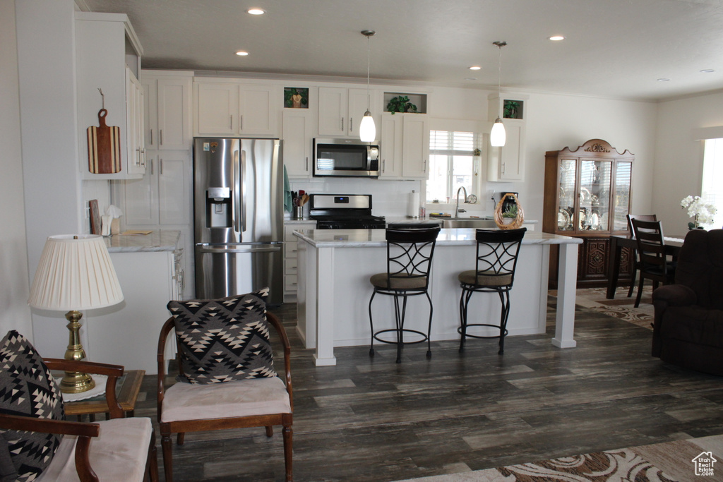 Kitchen featuring dark wood-type flooring, white cabinetry, stainless steel appliances, and pendant lighting