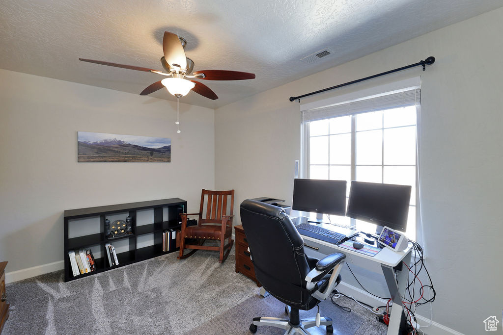 Carpeted home office with a textured ceiling and ceiling fan