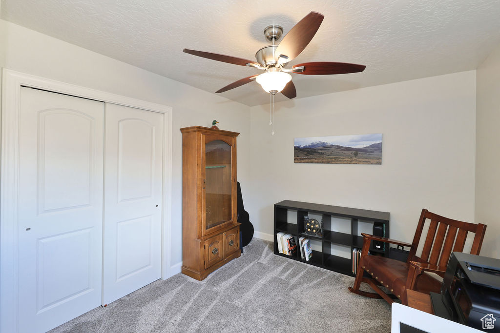 Misc room featuring dark colored carpet, a textured ceiling, and ceiling fan