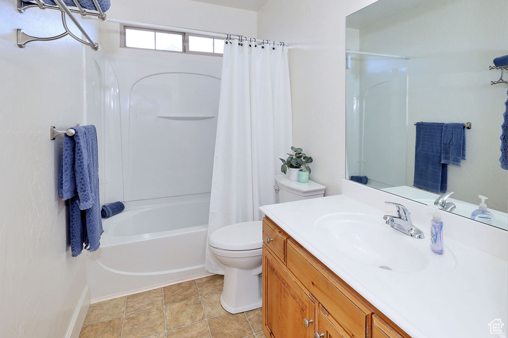 Full bathroom featuring tile floors, shower / bath combo with shower curtain, vanity, and toilet