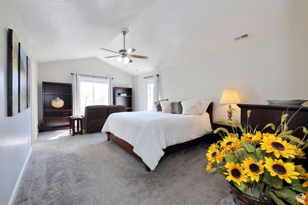 Bedroom featuring a textured ceiling, lofted ceiling, light colored carpet, and ceiling fan