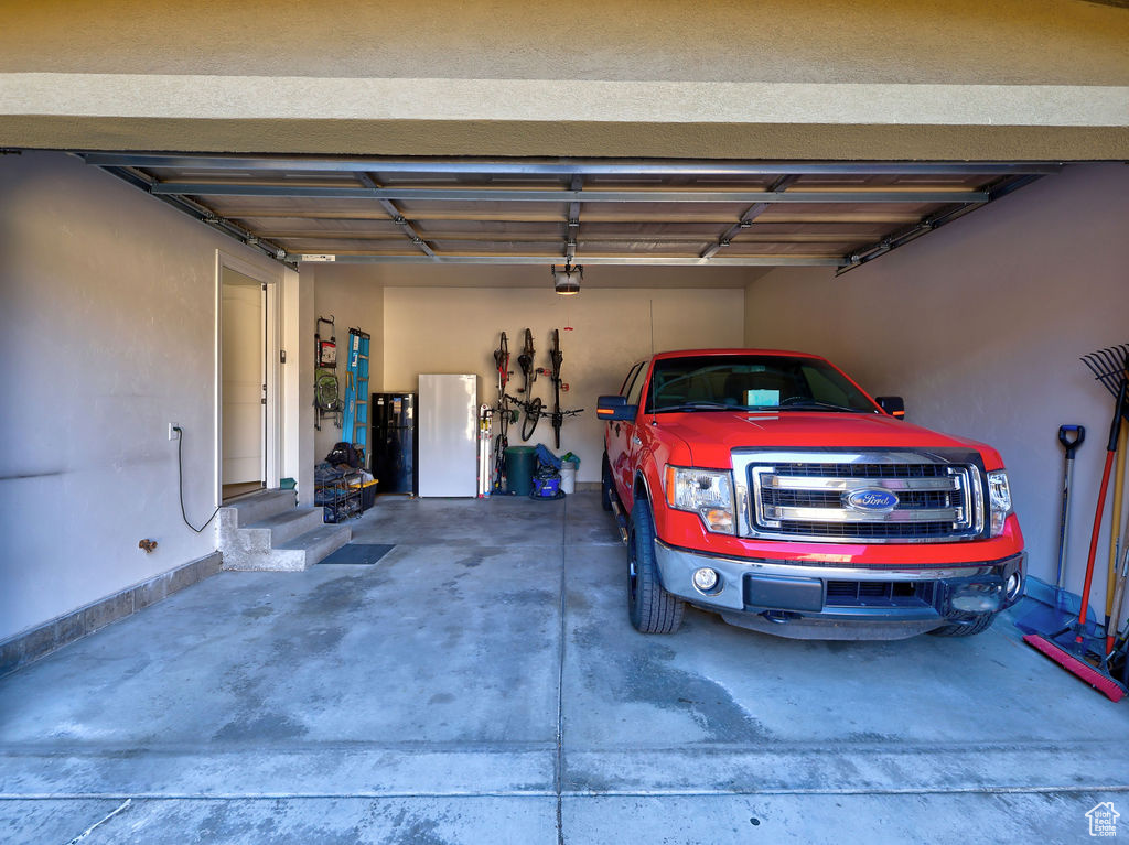 Garage featuring white fridge and a garage door opener
