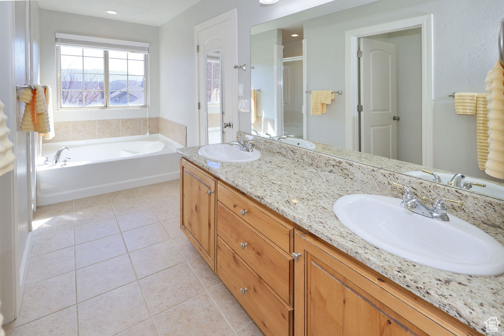 Bathroom featuring dual bowl vanity, tile flooring, and a bath