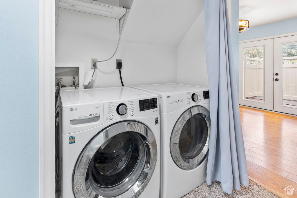 Laundry room featuring electric dryer hookup, light hardwood / wood-style flooring, washer and clothes dryer, and french doors