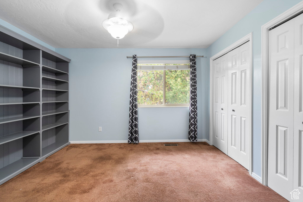 Unfurnished bedroom featuring two closets, light carpet, and ceiling fan