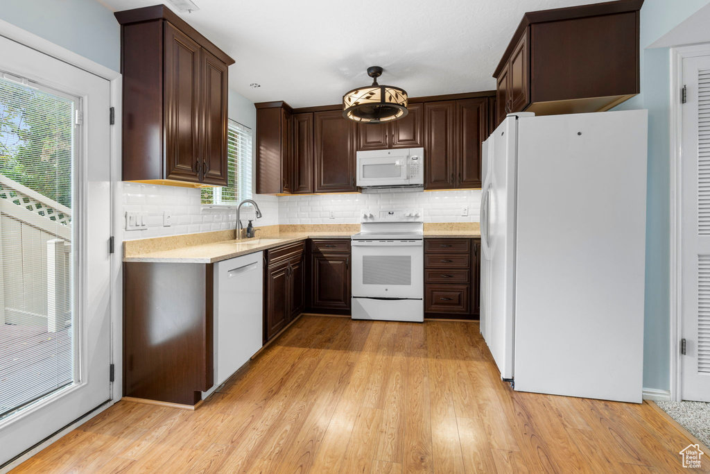 Kitchen featuring a healthy amount of sunlight, white appliances, light hardwood / wood-style flooring, and backsplash