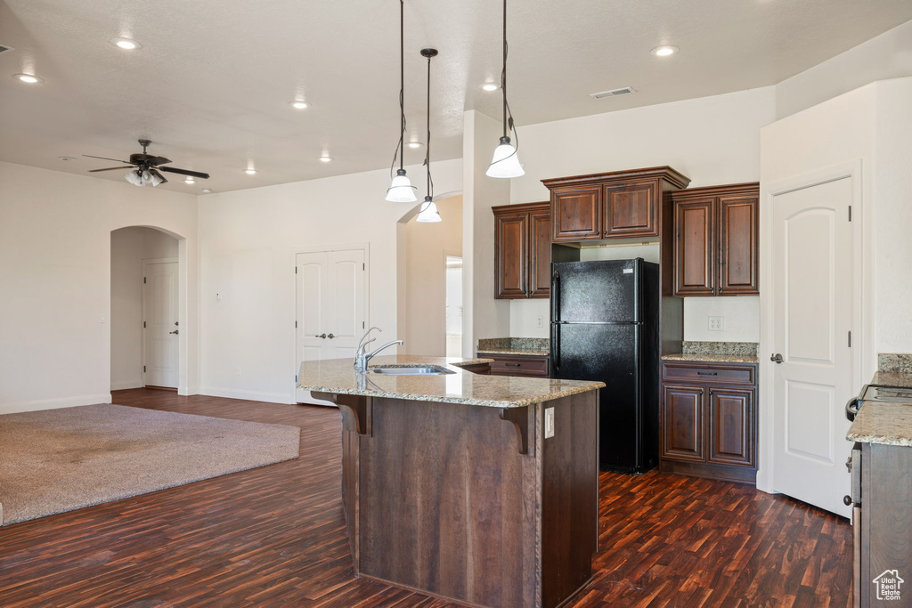 Kitchen with ceiling fan, dark hardwood / wood-style flooring, decorative light fixtures, and black fridge