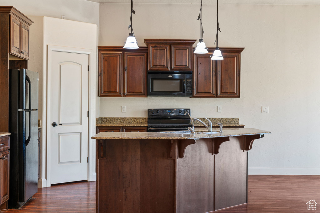 Kitchen with stainless steel refrigerator, dark hardwood / wood-style floors, hanging light fixtures, light stone countertops, and electric stove