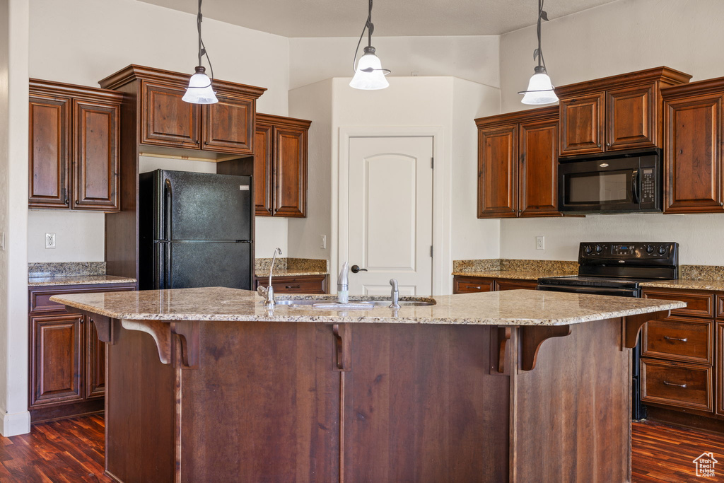 Kitchen featuring black appliances, pendant lighting, a breakfast bar area, and dark hardwood / wood-style flooring
