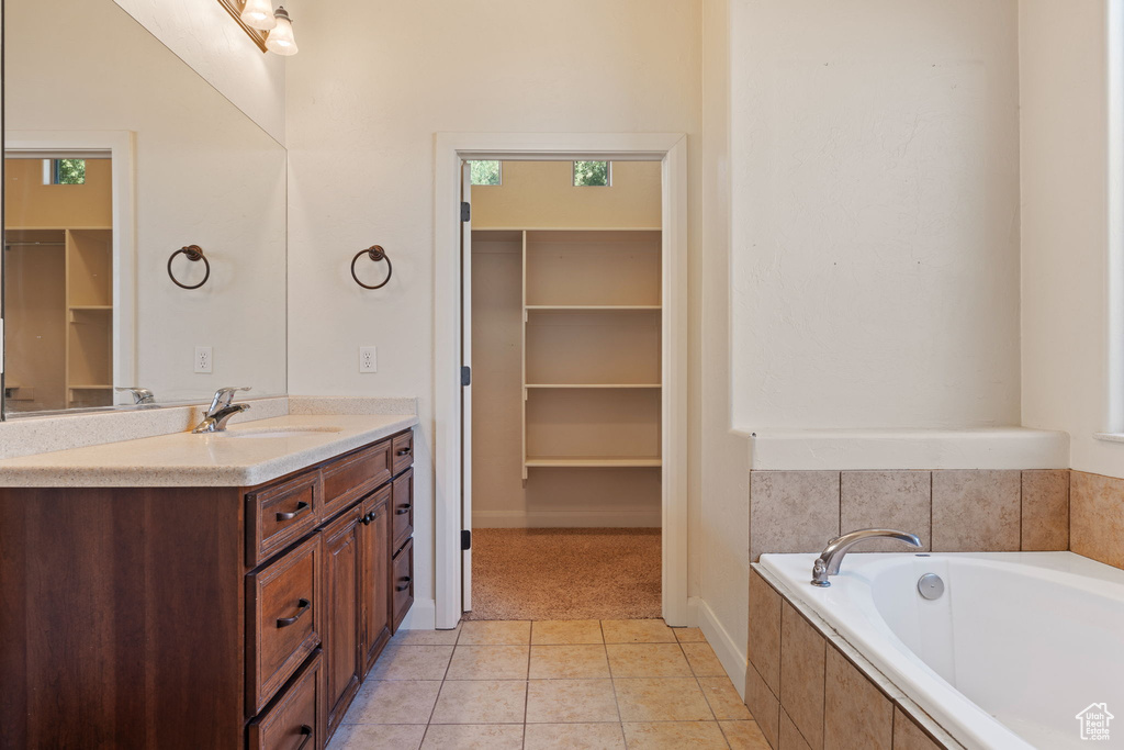 Bathroom featuring tile floors, vanity, and tiled bath