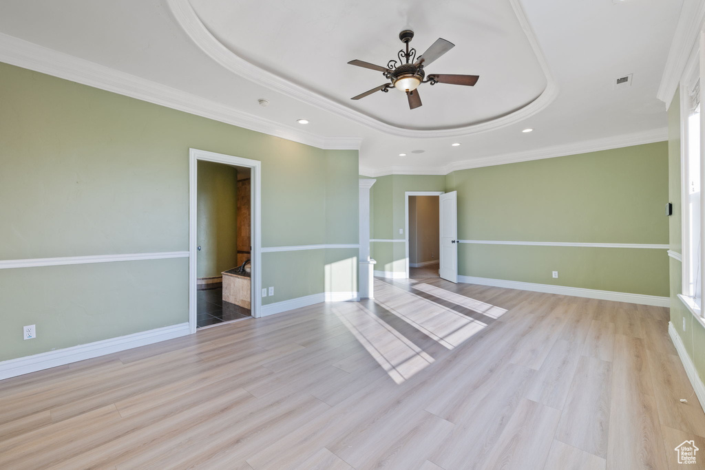 Spare room with a tray ceiling, ceiling fan, and light hardwood / wood-style flooring